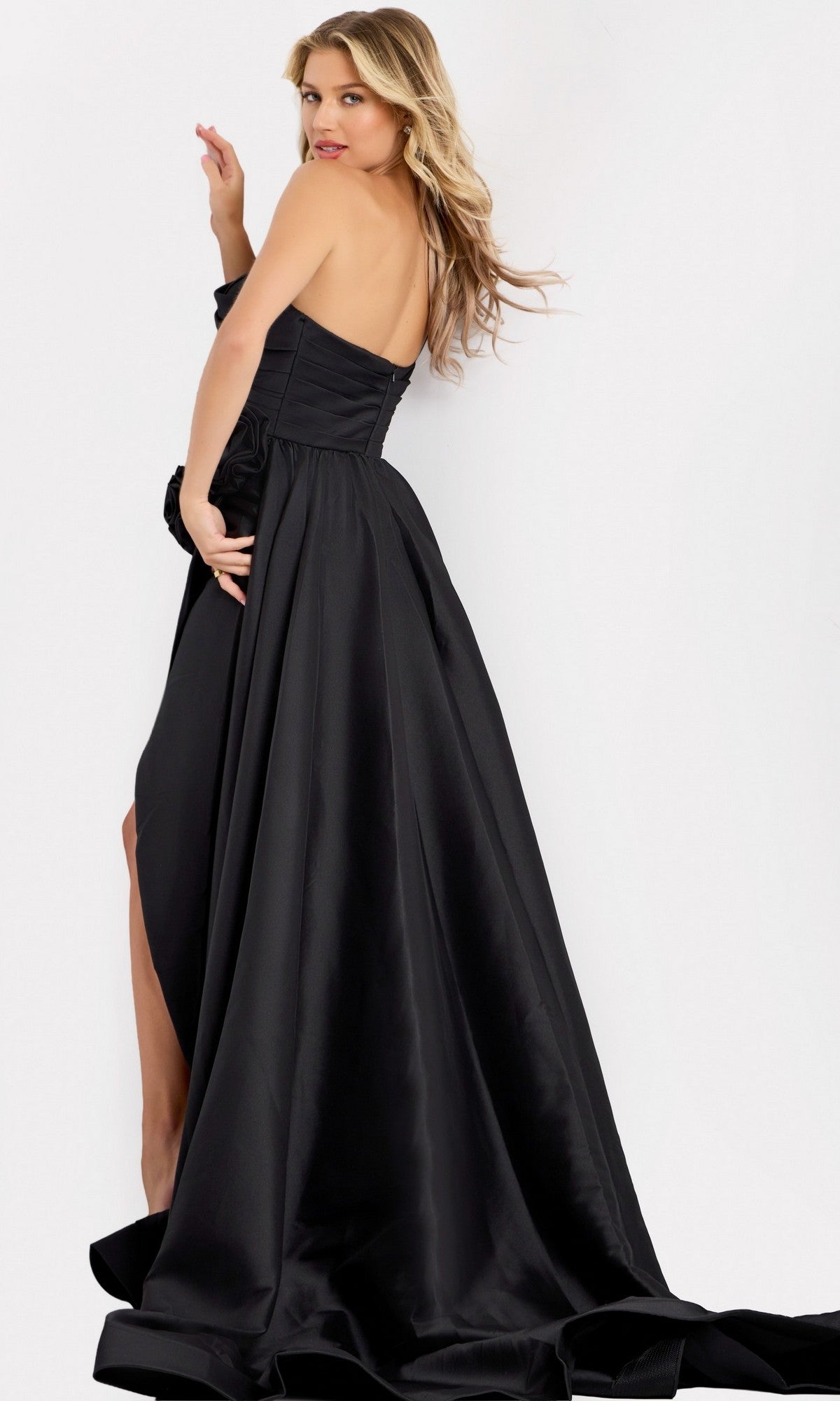 A woman poses in the Long Prom Dress: Jovani 48450, featuring a satin finish, flowing skirt, and high slit, set against a plain light background.